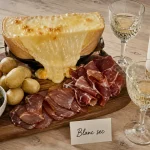 Vin blanc avec la raclette : planche de raclette et verres de vin blanc